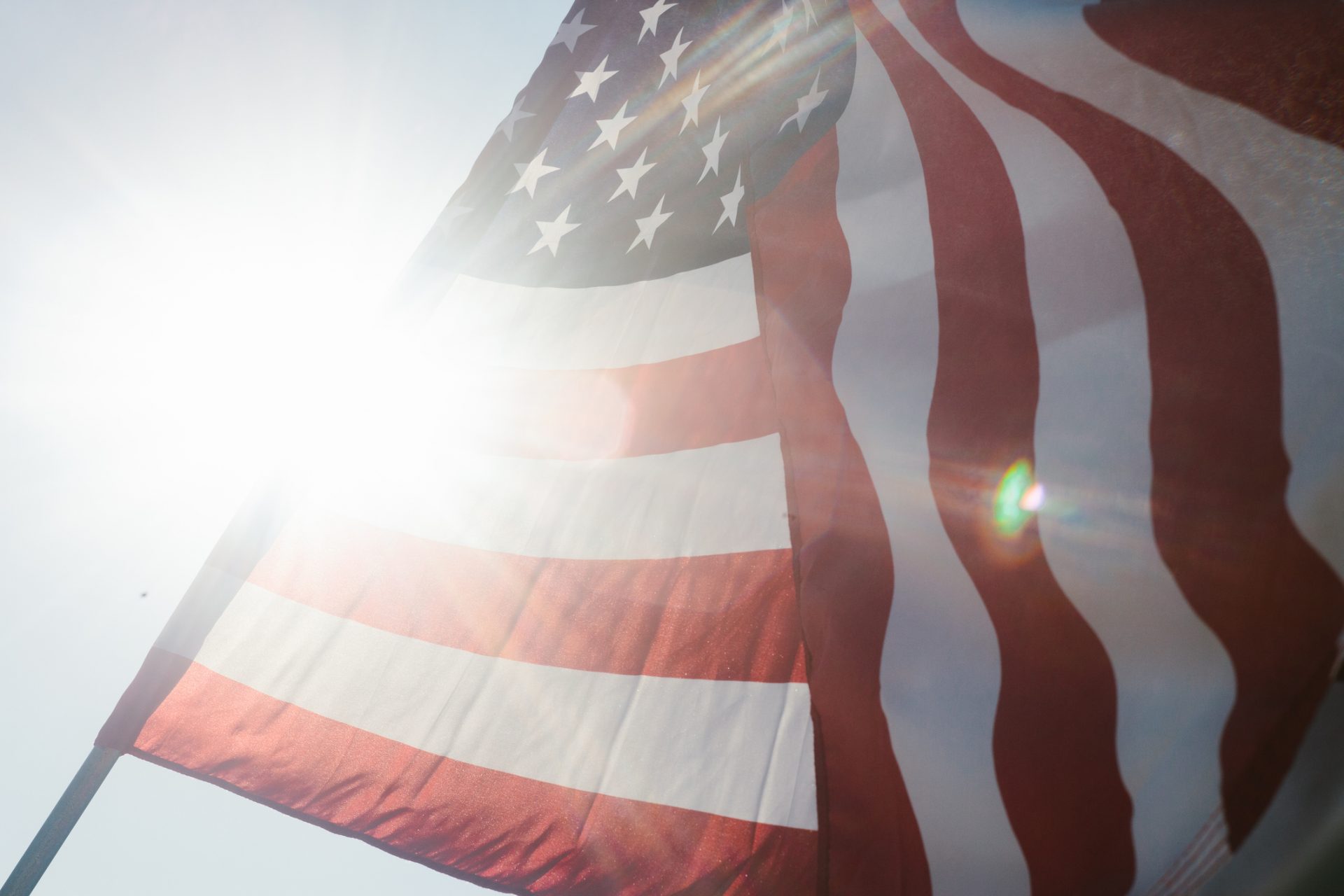 GettyImages-1458900856 Close-up of the American flag waving in bright sunlight with a lens flare effect behind it.
